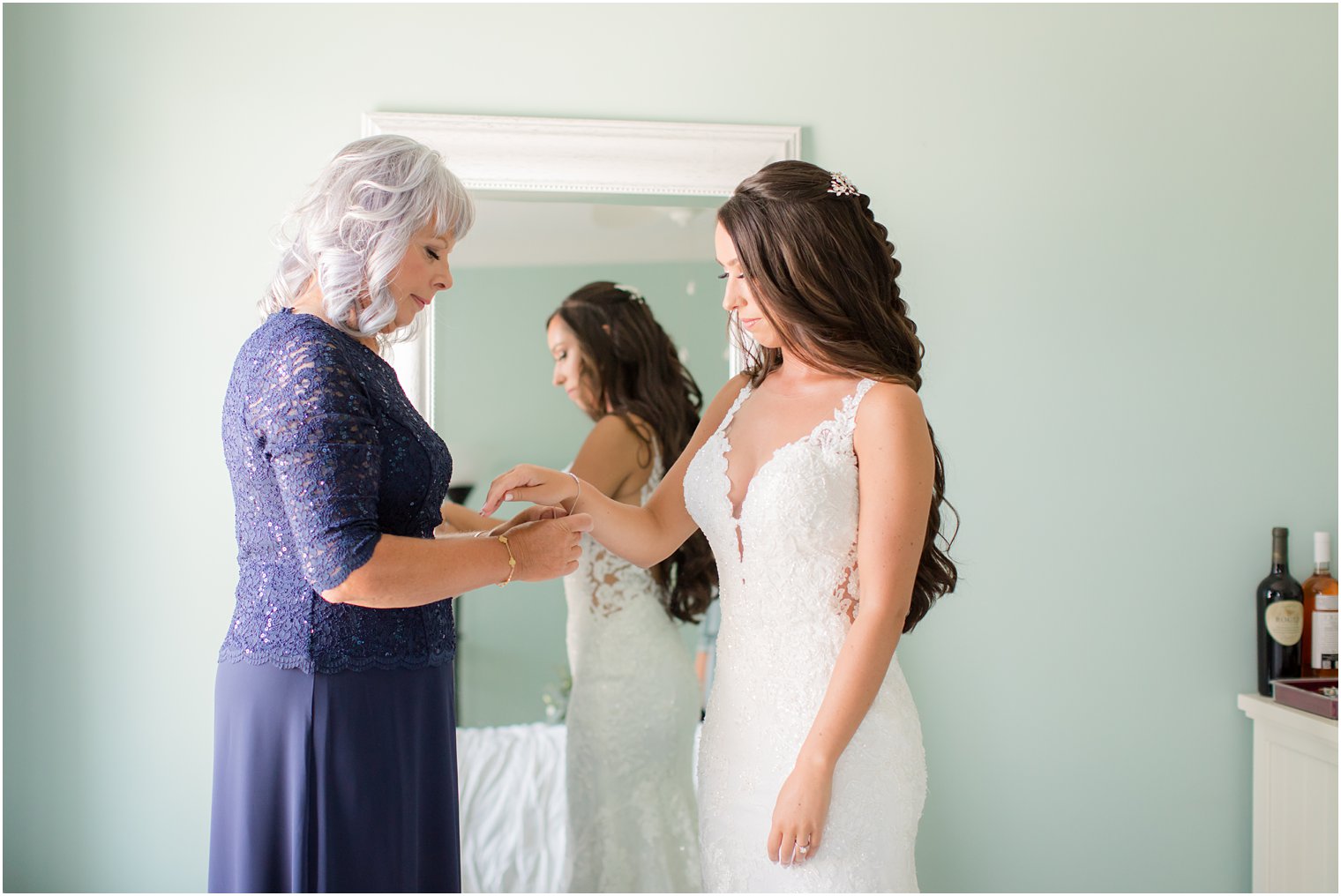 mother helps daughter with jewelry on wedding day