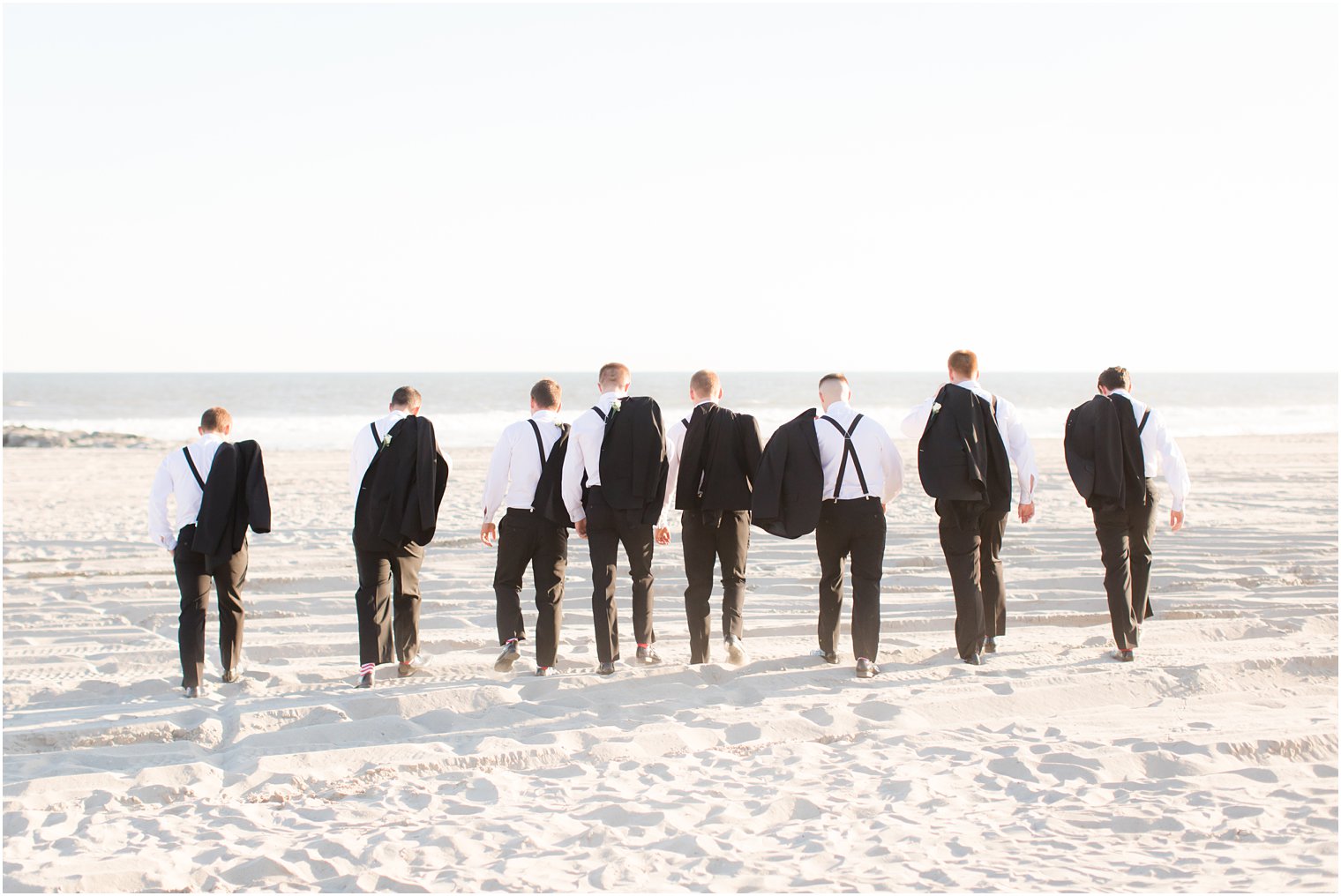 groomsmen walk on beach during wedding photos with Idalia Photography