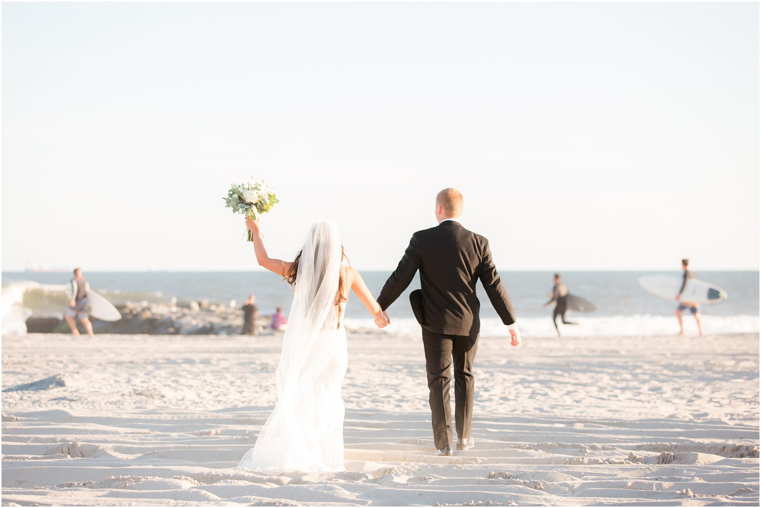 bride and groom walk down beach with Idalia Photography