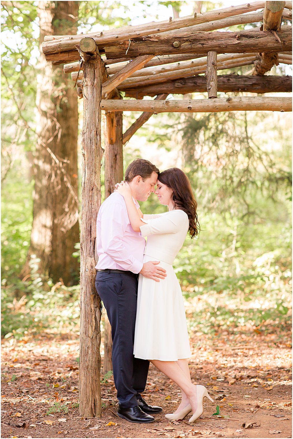 engaged couple leans against wooden structure on Watchung Reservation