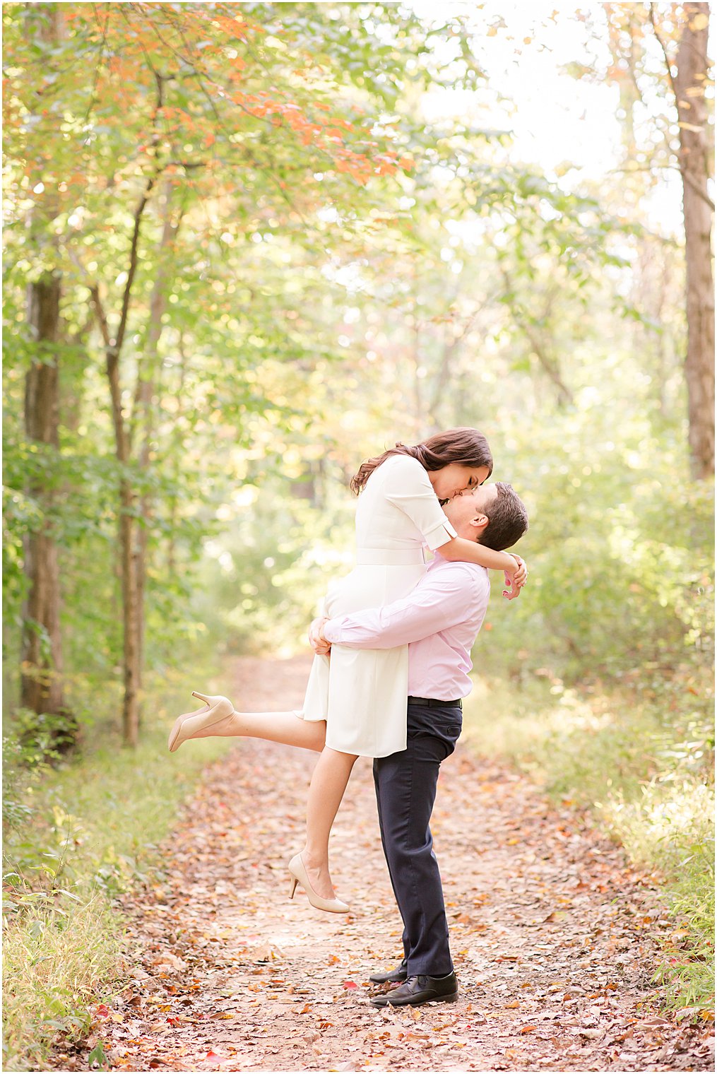 groom lifts bride to be up during engagement photos kissing her