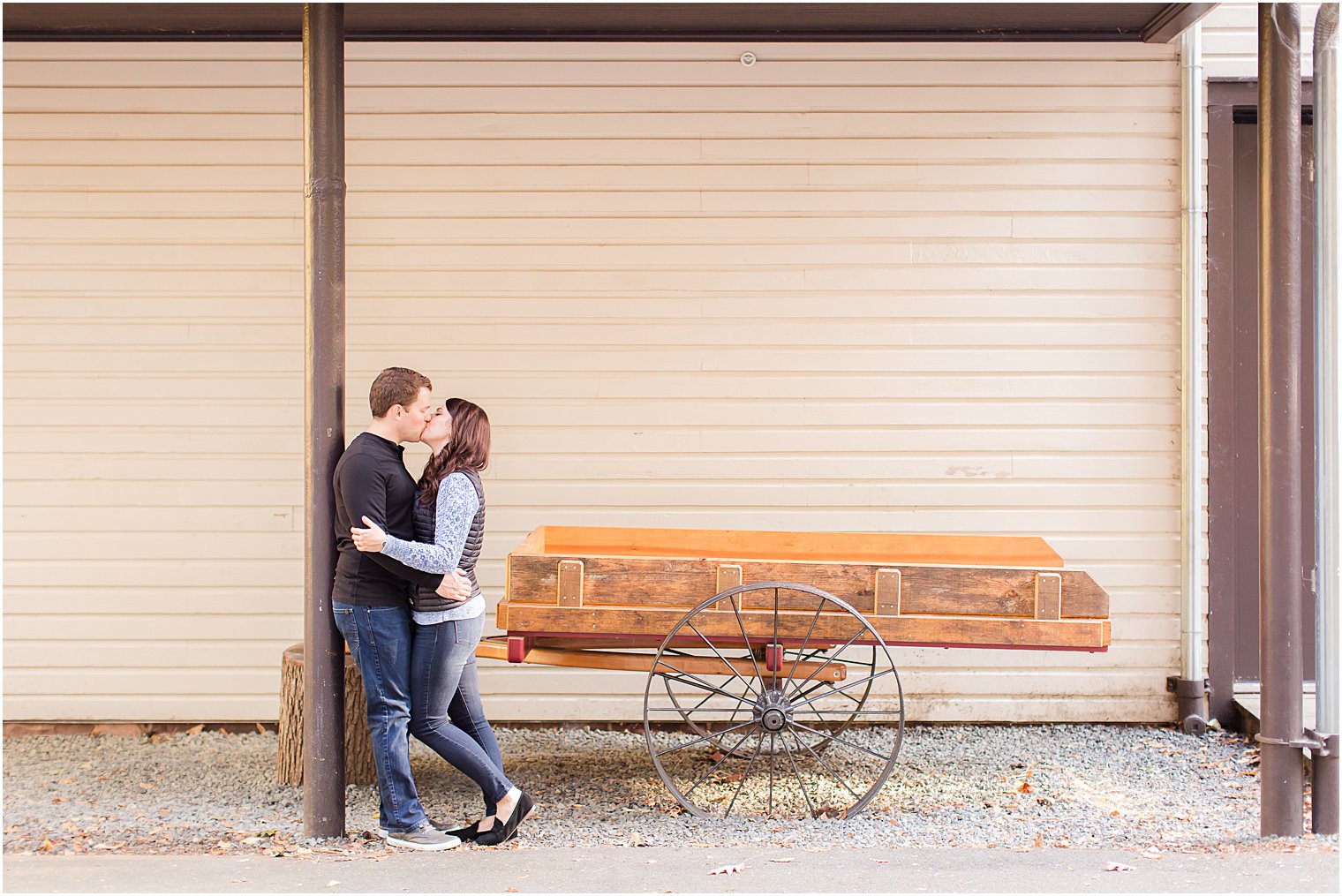 bride and groom kiss by old wagon at Watchung Reservation