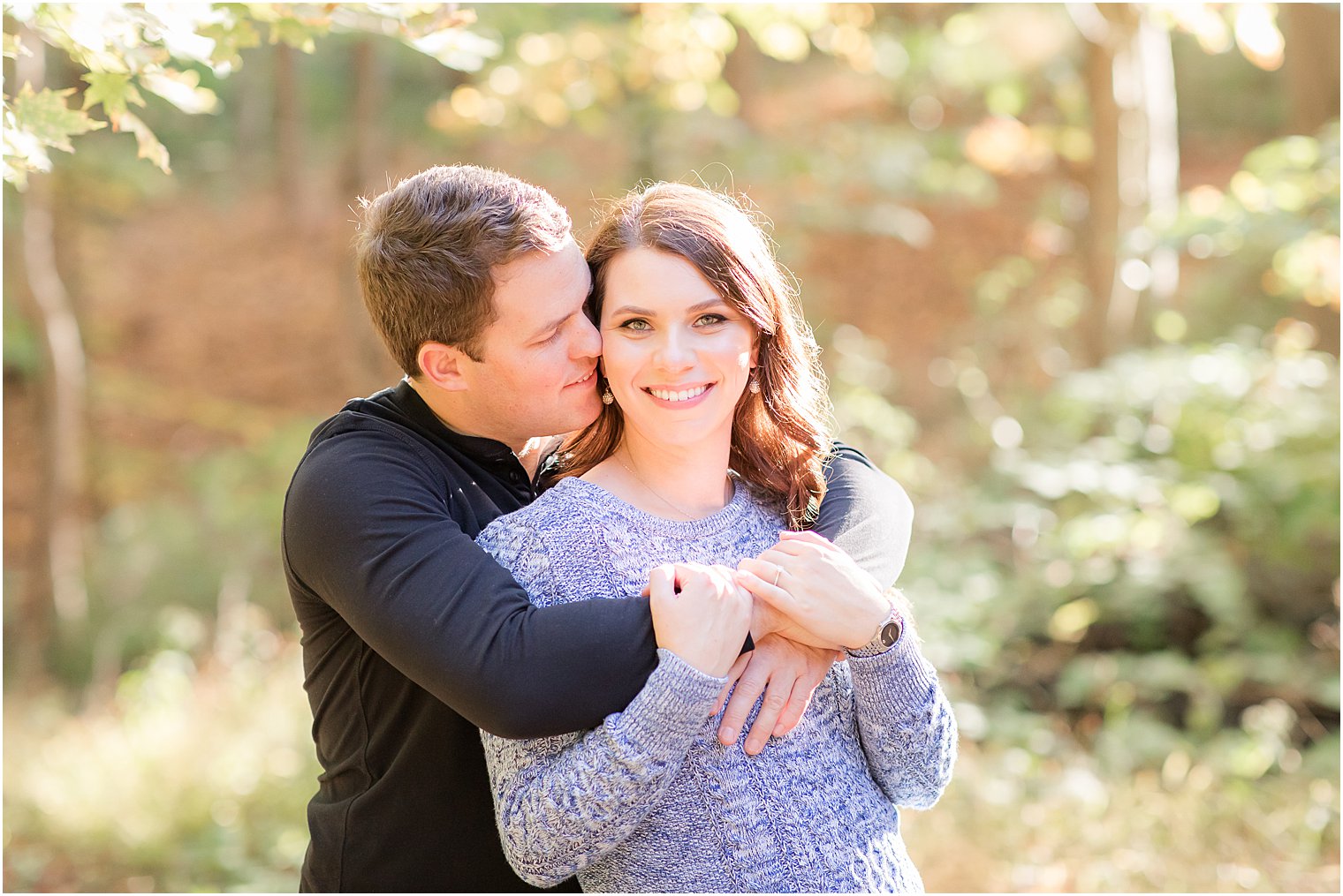 groom hugs bride from behind during Watchung Reservation engagement session