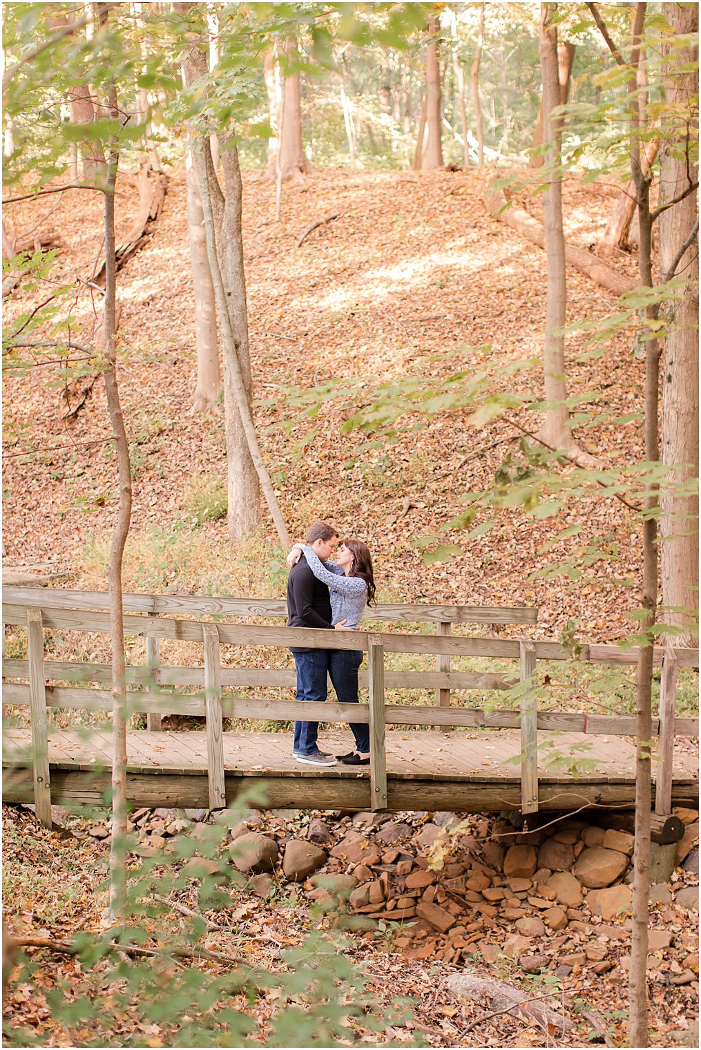 couple stands on bridge in woods during Watchung Reservation Engagement Session