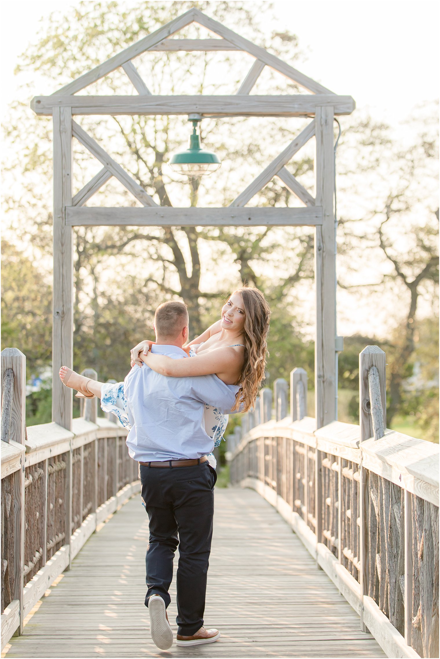 groom carries bride across Spring Lake bridge