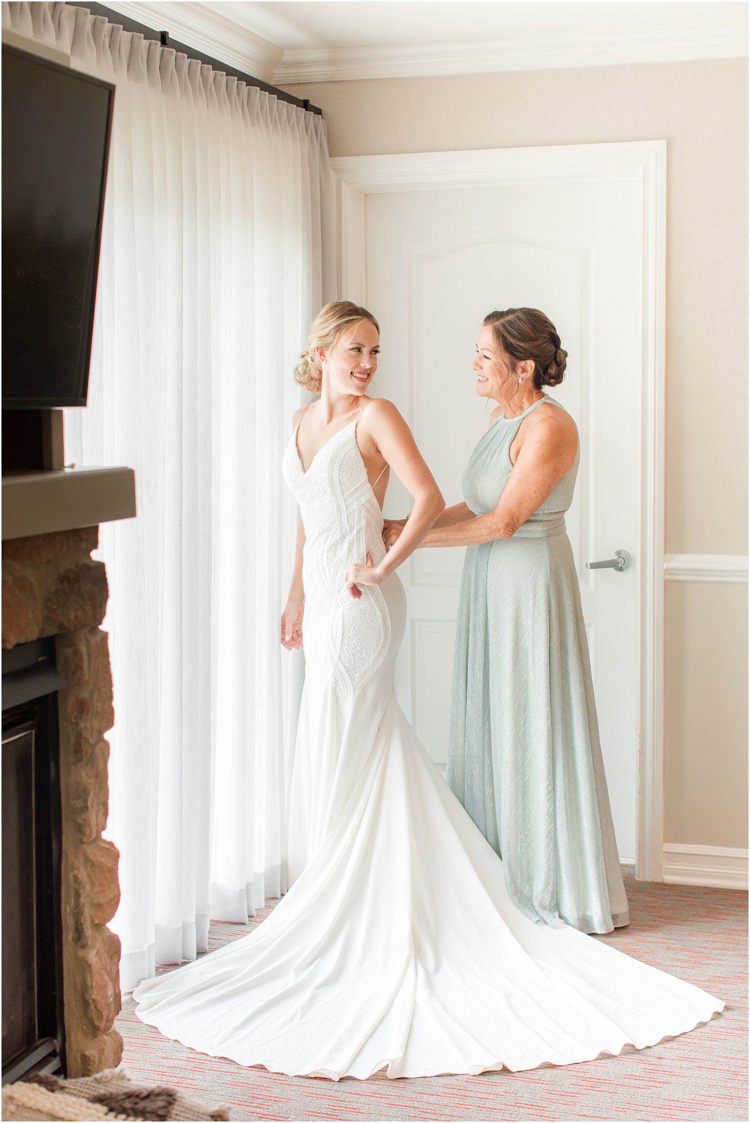 mother helps bride with wedding gown before NJ wedding