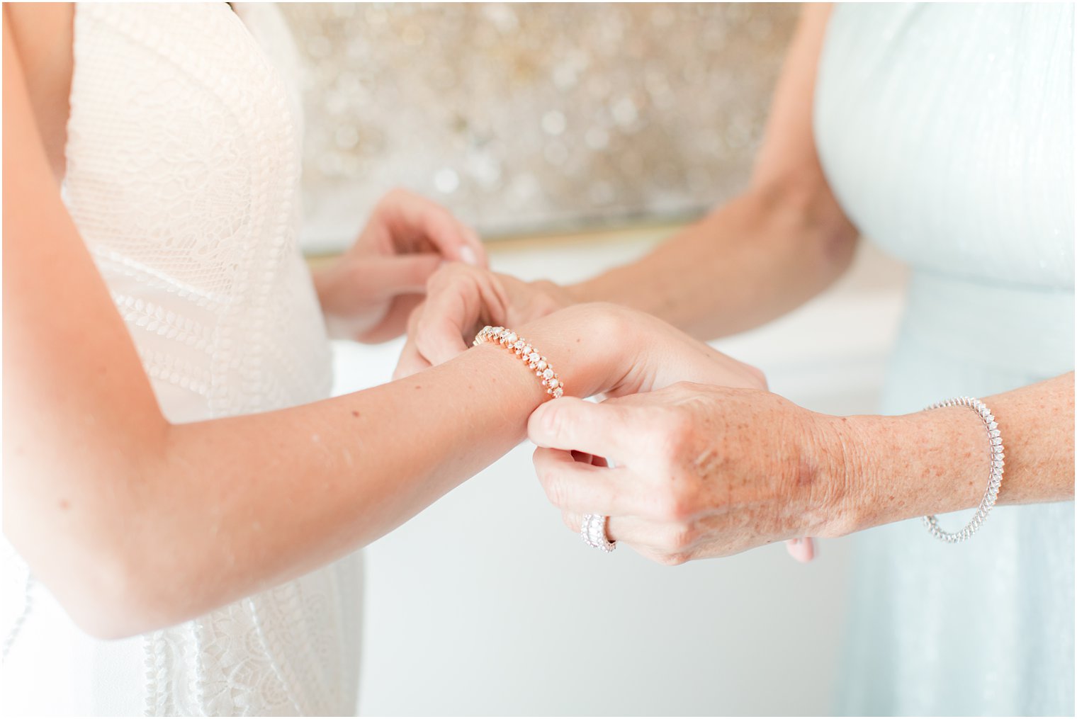 mother helps bride with bracelet on wedding day