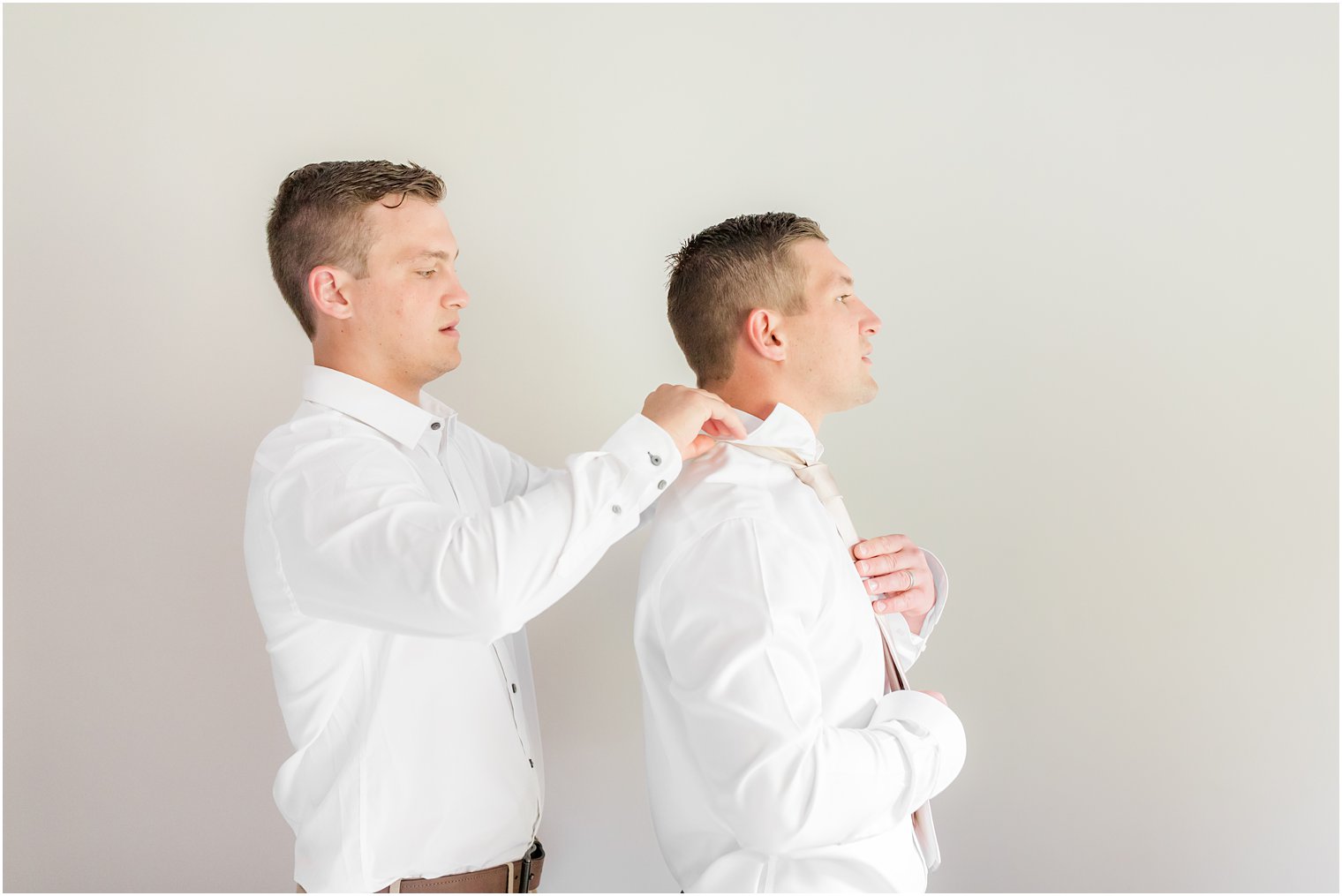 groomsman helps groom adjust tie for NJ wedding day 