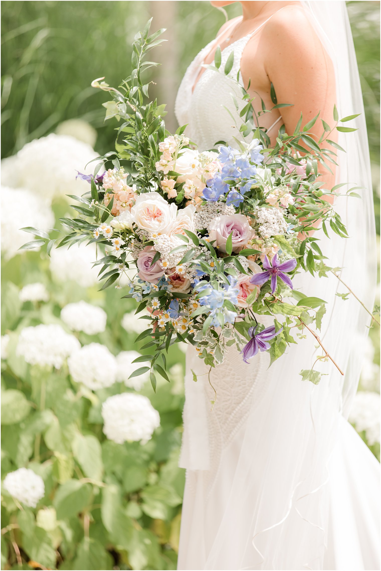 bride holds bouquet of roses and wildflowers for summer wedding in New Jersey