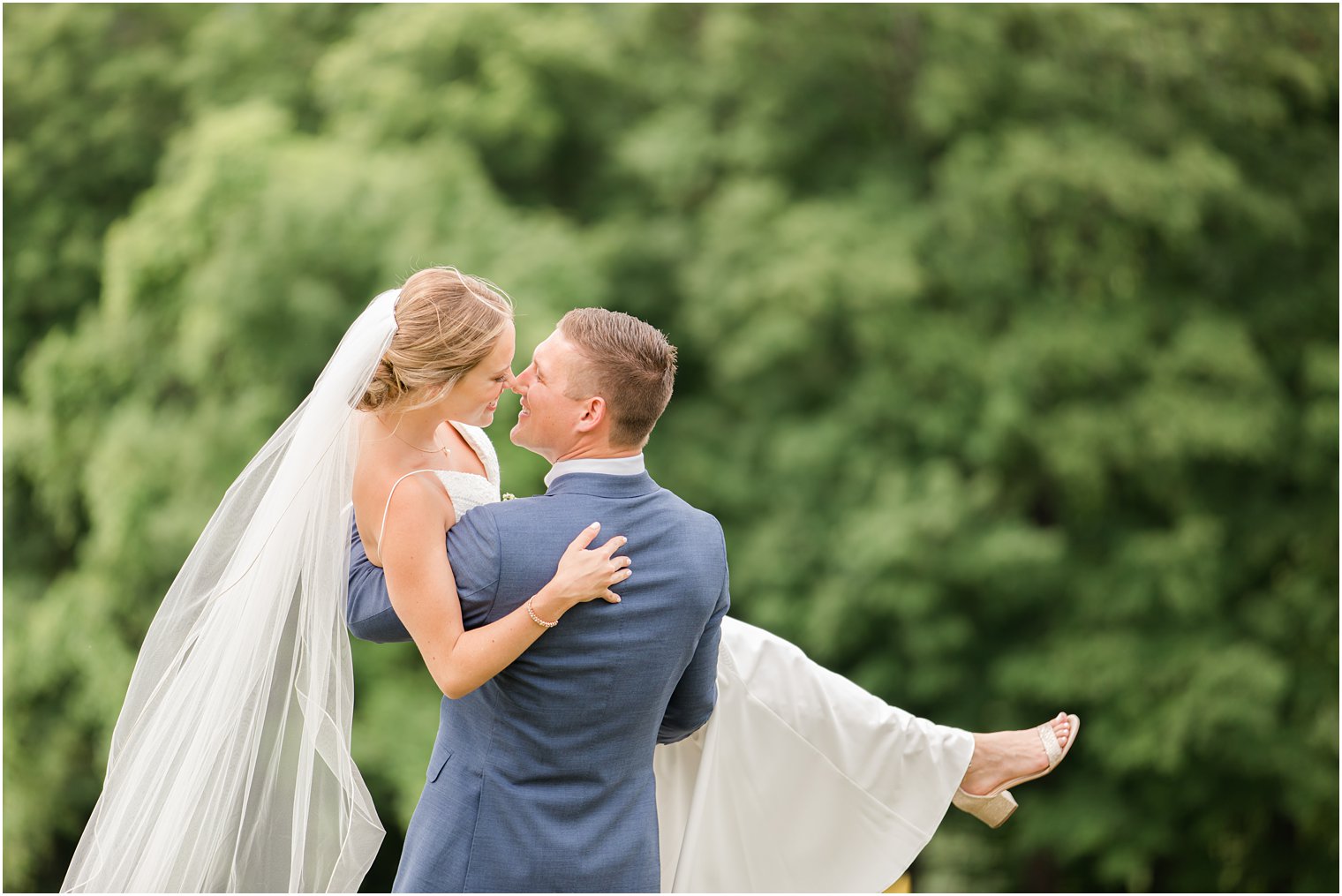 groom holds bride up and touches her nose on wedding day