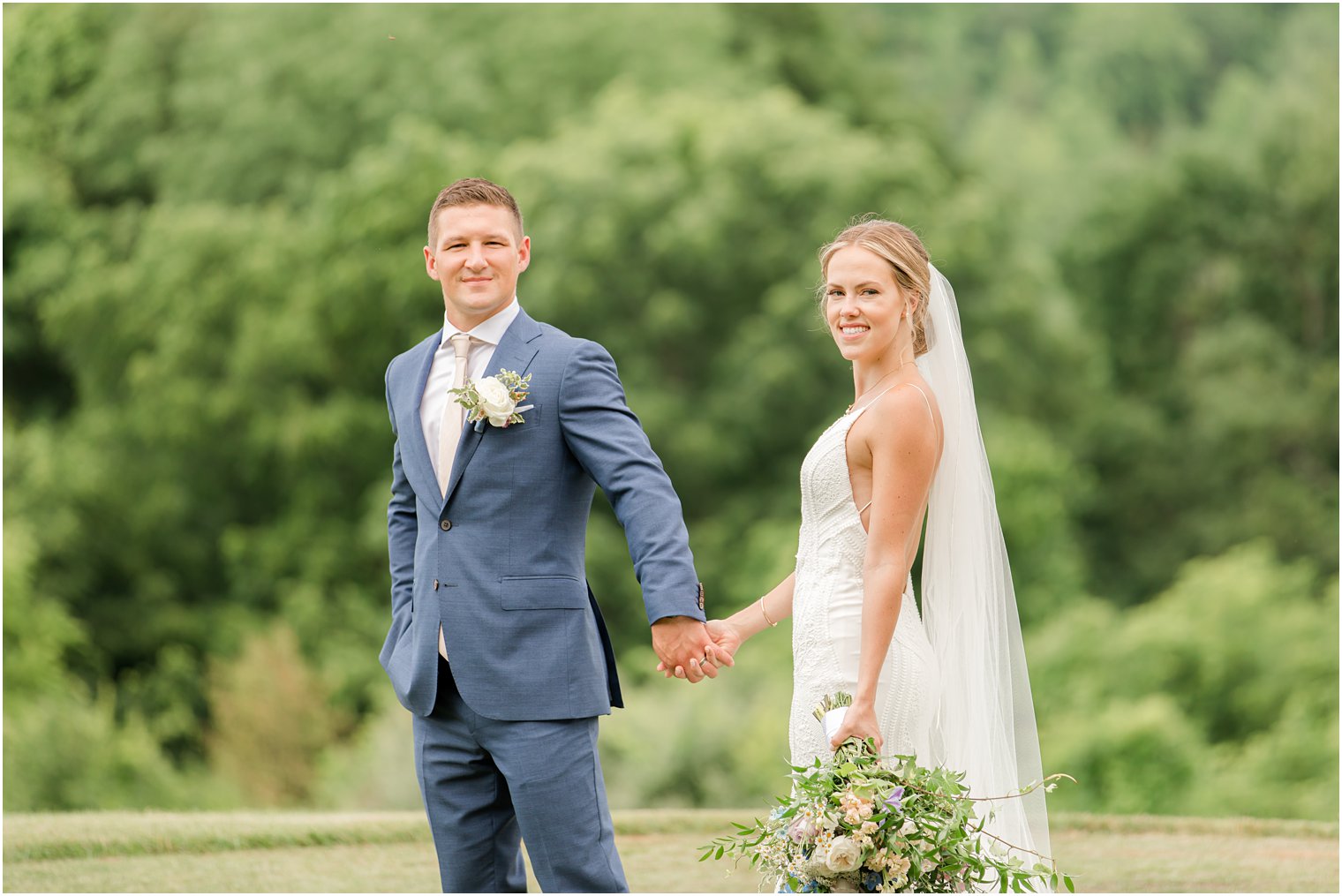 bride and groom hold hands walking through field in New Jersey 