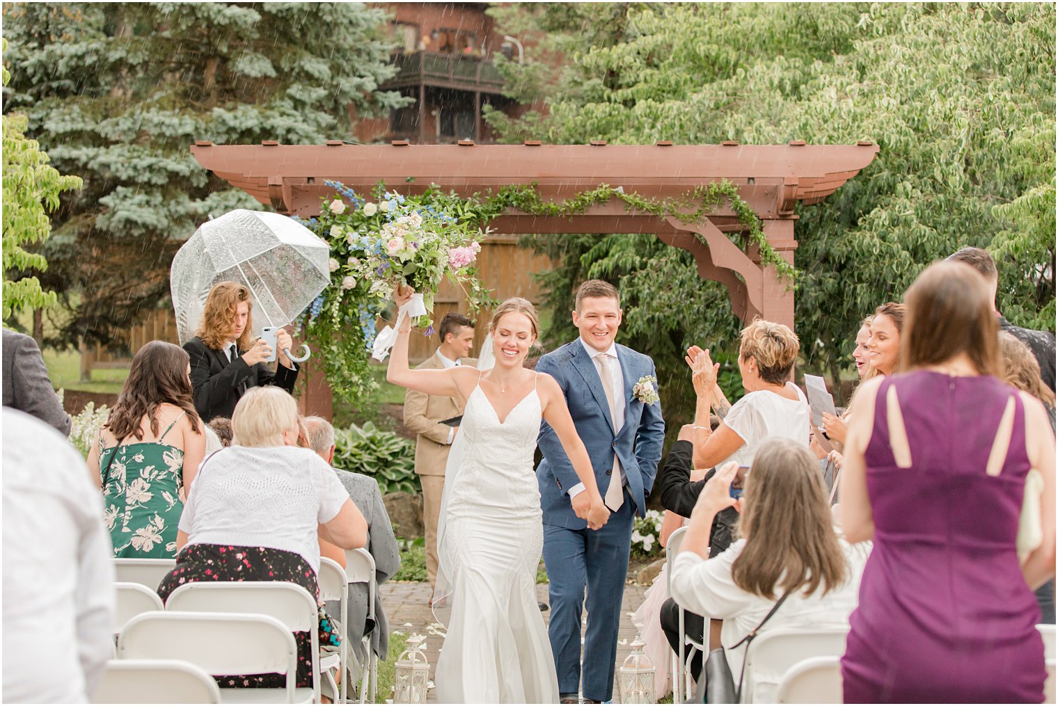 bride and groom laugh walking up aisle after wedding ceremony in the rain