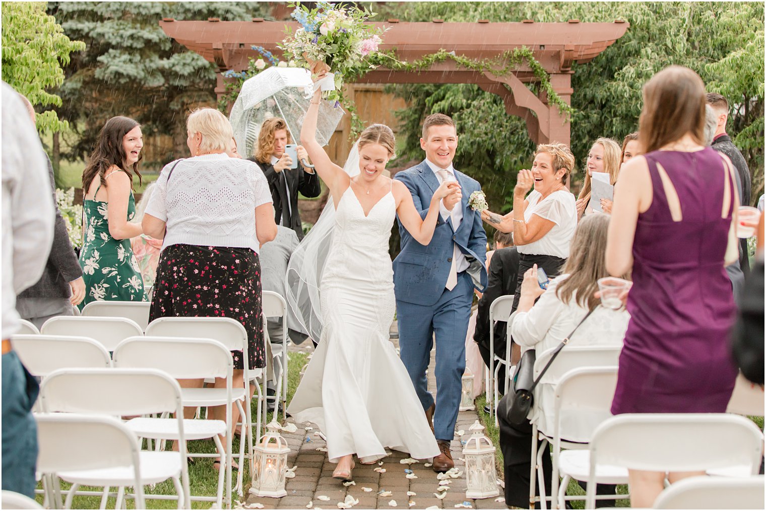 newlyweds cheer walking up aisle in the rain on wedding day