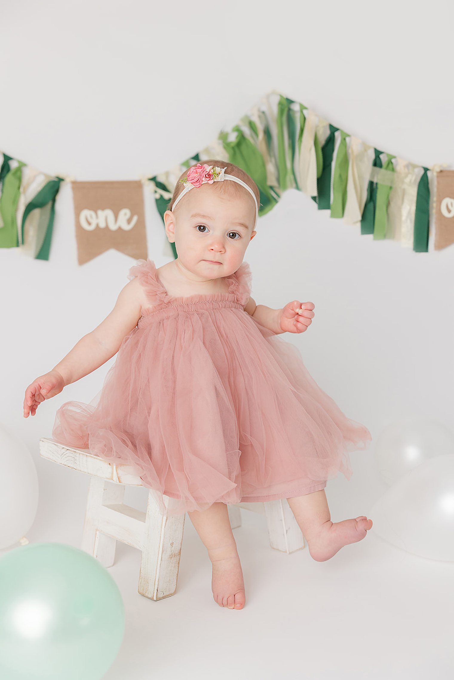 baby girl sitting on a chair posing for her one year session