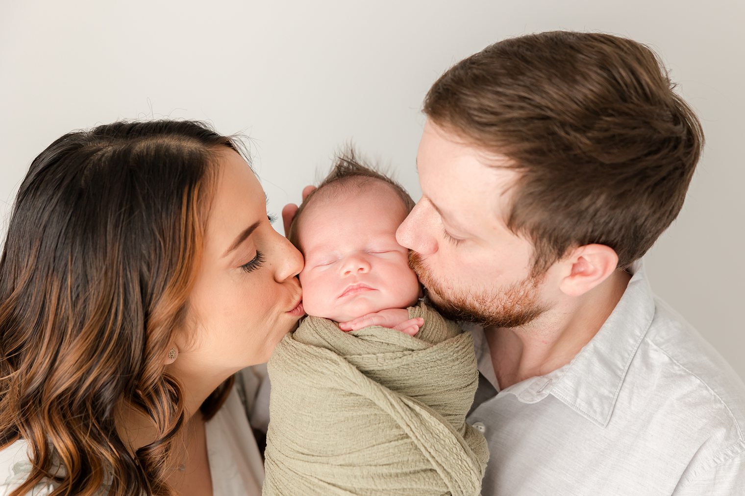 mom and dad kissing their baby boy