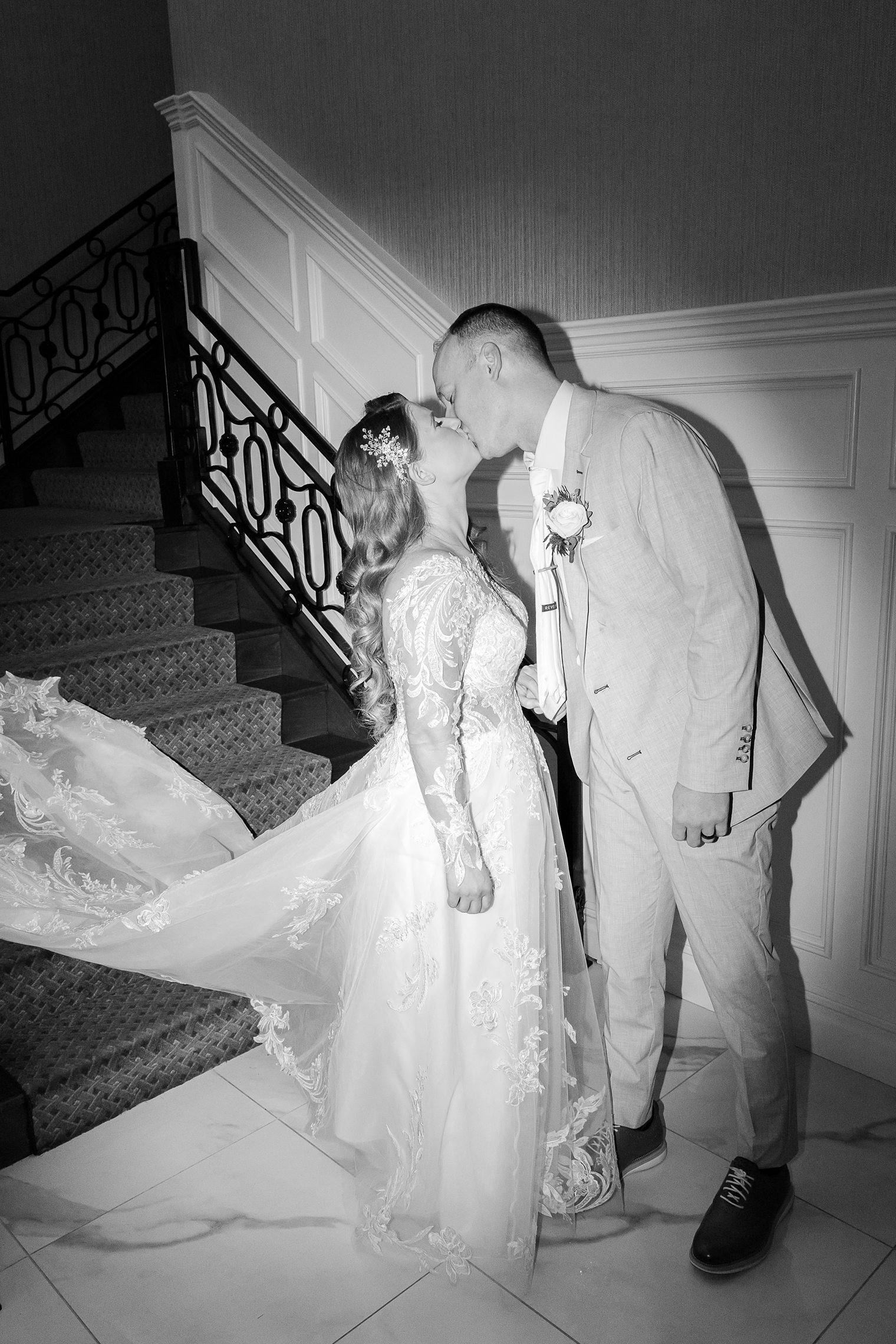 husband and wife sharing a kiss in front of the stairs 