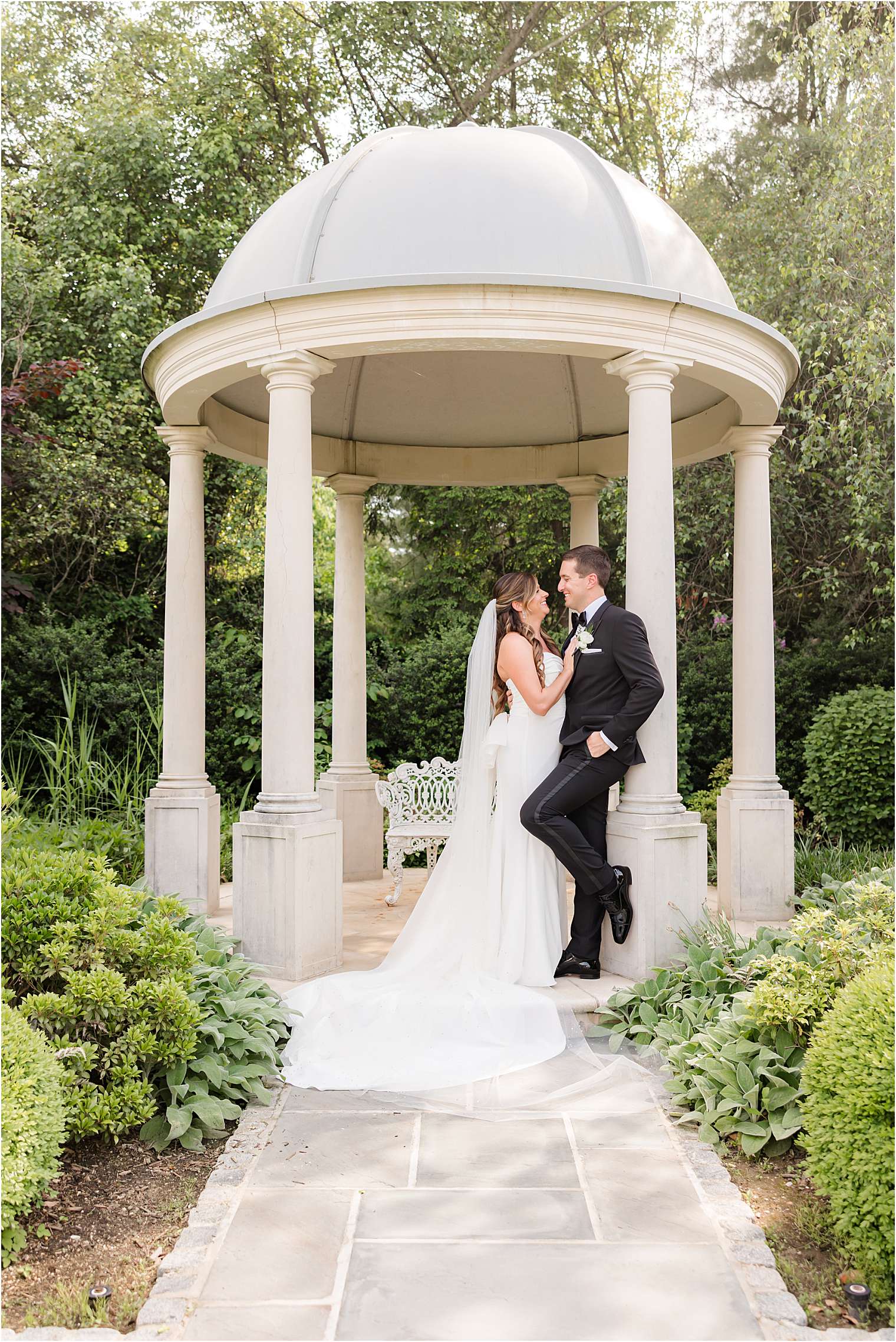 A bride and groom share a romantic moment under a white gazebo 