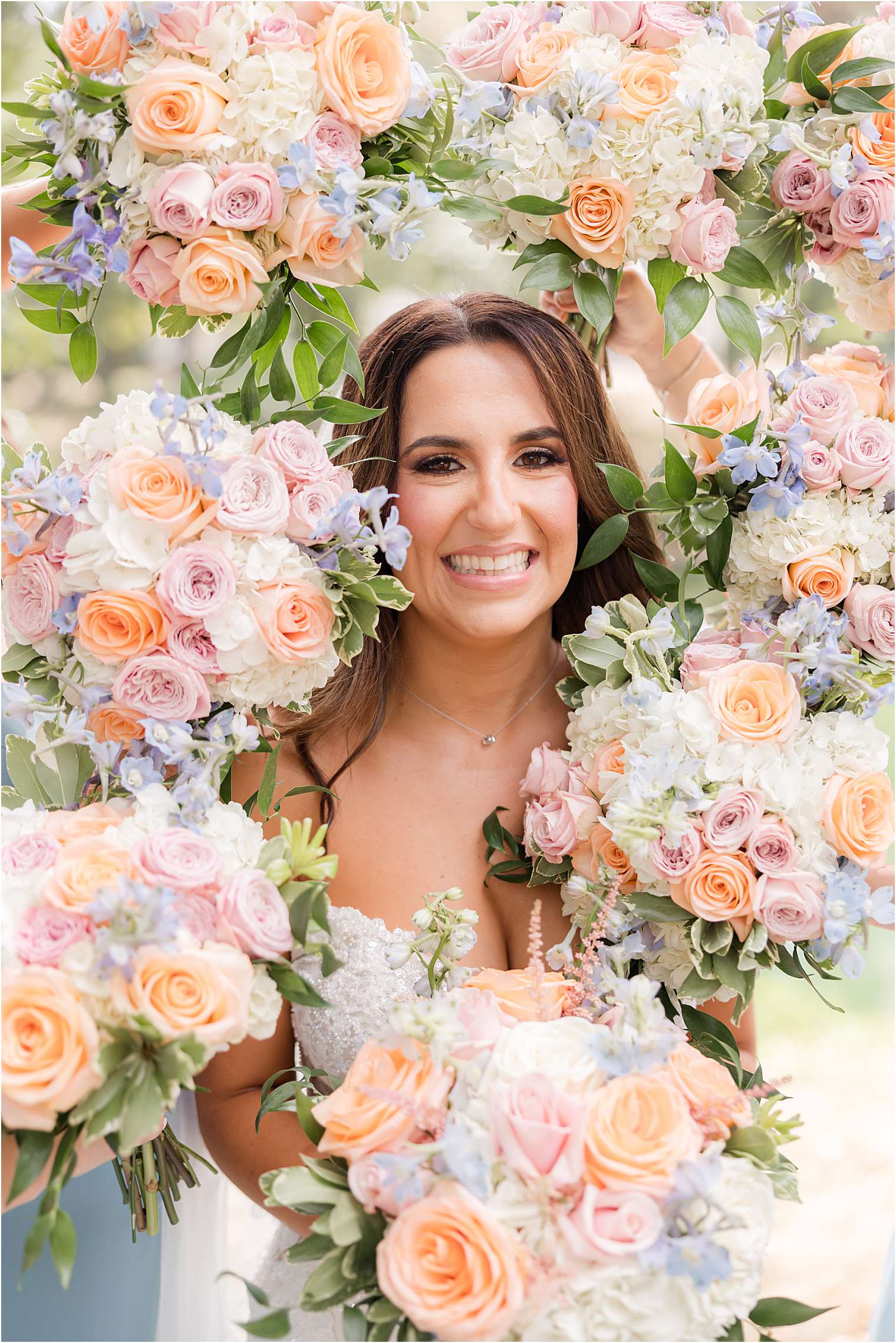 Bride posing surrounded by beautiful pastel-colored flower bouquets.