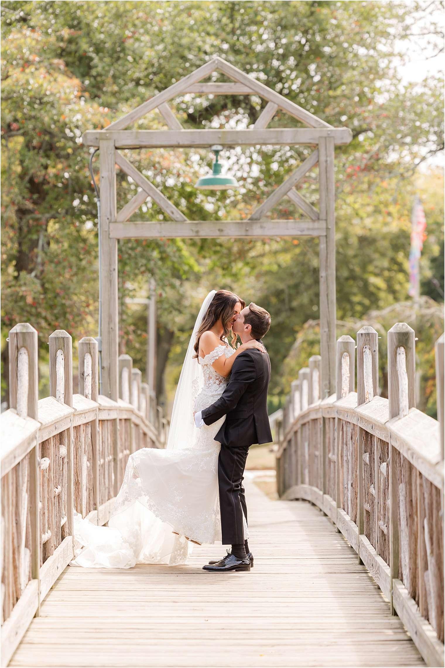 Bride and groom walking across a bridge in daylight.